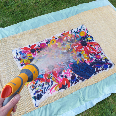 Felted flowers being rinsed with hose in garden